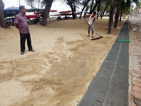 Beach vendors brush sand off the footpath to prove that it was all buried.