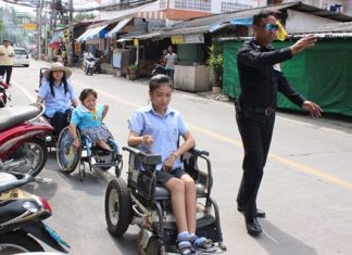 In this case, in front of the press, a friendly traffic officer helps wheelchair users negotiate motorcycles parked in the wheelchair path as city officials and police inspect the area (in the background).