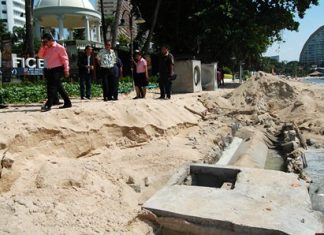 Officials inspect the area of Wong Amat Beach where heavy rain interrupted construction of new waste water pipes, causing sewage to empty into the sea.
