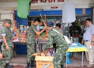 District Chief Phawat Lertmukda (right) leads a team of volunteers, police and navy personnel through the Sattahip Market raiding vendors selling firecrackers and khom loys.
