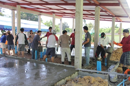 Many more volunteers lend a hand to mix concrete for the new preschool building.
