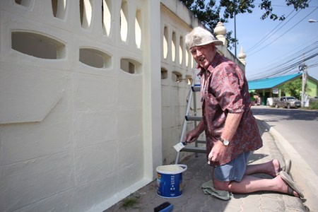 Briton Terry Smith takes a break from painting the wall at Sutthawat Temple to smile for a photo.