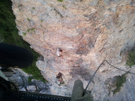 A member of the Navy’s SEAL team is lowered down to pluck the stranded Greek from the side of the cliff.