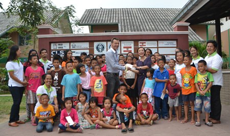 Rudolf Hofer presents the money to Radchada Chomjinda, surrounded by the children.