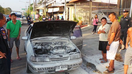 Singhnart Wattanasri (front, right) looks over his burnt out car as others try to console him.
