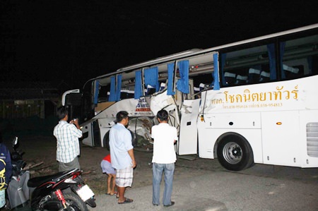 Onlookers stare at the damaged bus after an accident that killed one man and seriously wounded five others in Pong Sub-district.