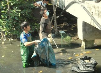 Volunteers clean out garbage, leaves, broken branches and other obstructions to water flow from Nok Yang Canal in Naklua.