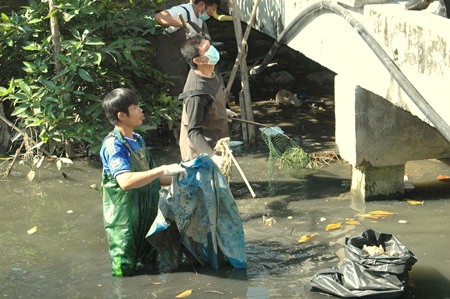 Volunteers clean out garbage, leaves, broken branches and other obstructions to water flow from Nok Yang Canal in Naklua.
