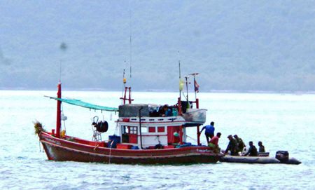 Royal Thai Navy officials board a local fishing boat to check for human trafficking.