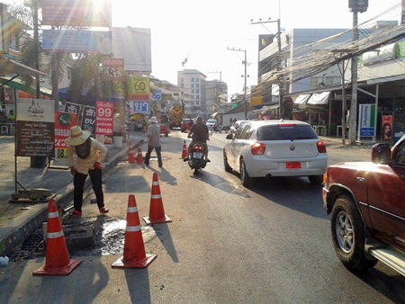 Contractors are working on manhole covers, making them level with the surface of the road.