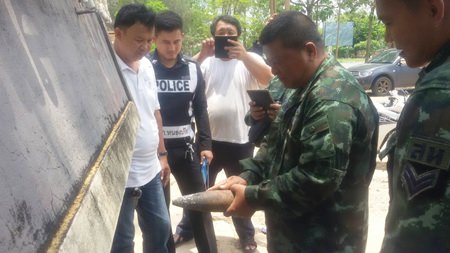 Police and military personnel inspect the old and rusted ordinance.
