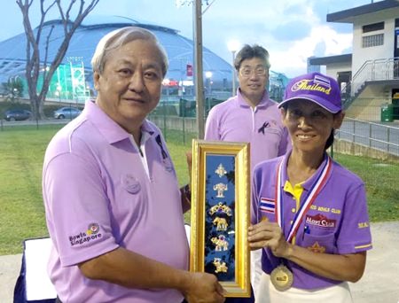 Coco Club’s Sue Bryant (right) wearing a silver medal as runner-up in the ladies singles, presents Tan Kah Hock, the President of the Singapore Lawn Bowls Association, with a Thailand memento.