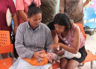 Motherly women crowd around the abandoned child. Wilai Tonelung (right) found the infant lying in a foam box at her family’s banana plantation in Sattahip.