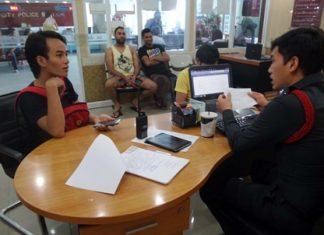 Jettarin Boonmarong (left) makes a report at the police station, stating that a foreigner cheated him out of 32,000 baht.