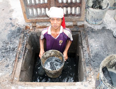 This is a prime example of the phrase, “It’s a dirty job but someone has to do it.” Dang holds up a bucket of sludge he and his fellow countrymen have been hired to dig out from the local drains.