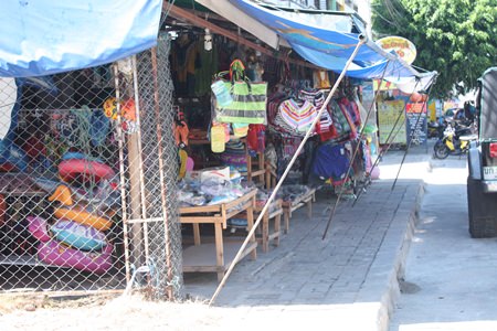 Vendors in Naklua are once again encroaching on public footpaths, causing pedestrians to veer out into the street to get past, as can be seen all the way down the street.