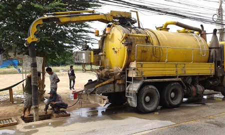 Workers from Mario Engineering Ltd., use vacuums and other equipment to suck rubbish, plastic bags, mud and other objects out of the drains along Soi Khao Talo.