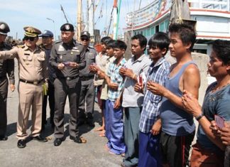 Workers aboard fishing vessels currently at port in Samae San hold up their legal papers and IDs for the police entourage to inspect.