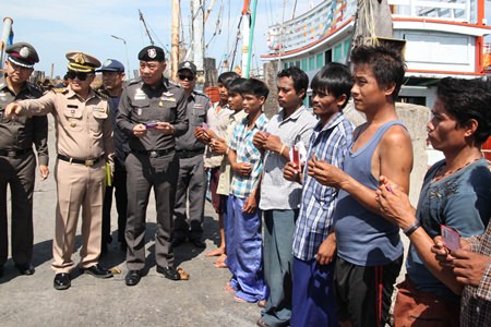 Workers aboard fishing vessels currently at port in Samae San hold up their legal papers and IDs for the police entourage to inspect.