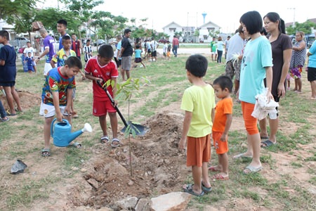 Youths and residences of the government housing village in Nernplabwan plant trees to spruce up the surroundings and help prevent erosion during the rainy season.