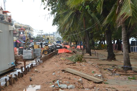 Workers on Jomtien Beach walk pavements halted construction during the storm.