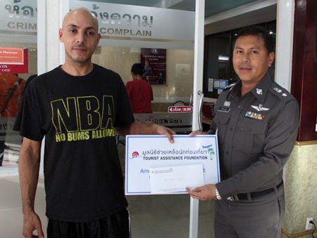 Briton Aser Ubus receives 6,000 baht from Kwanchanok Thana, representing the Tourist Assistance Foundation.