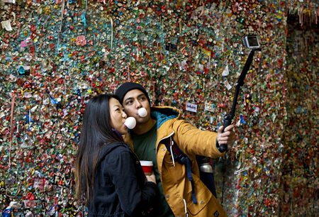 Jessica Wang, left, and Michael Teylan, both of Los Angeles, use a selfie stick at Seattle’s “gum wall” at Pike Place Market, Monday, Nov. 9, 2015. (AP Photo/Ted S. Warren)