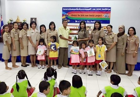 Members of the Rotary Club of Pattaya help stock the shelves of the Pattaya School No. 7 library with a donation of books.