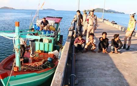 Captain and crew sit on a Thai Navy dock as officials search their tiny vessel.