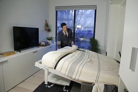 Stage 3 Properties co-founder Christopher Bledsoe demonstrates a retractable bed that turns into a sofa when stored inside one of the apartment units at the Carmel Place building in New York City. (AP Photo/Julie Jacobson)