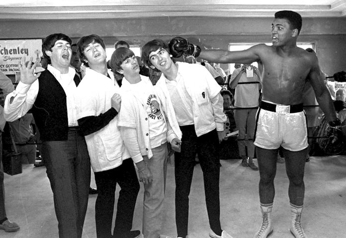 The Beatles (from left) Paul McCartney, John Lennon, Ringo Starr, and George Harrison, take a fake blow from Cassius Clay (Muhammad Ali) while visiting the heavyweight contender at his training camp in Miami Beach, Fla., Feb. 18, 1964. (AP Photo/File)