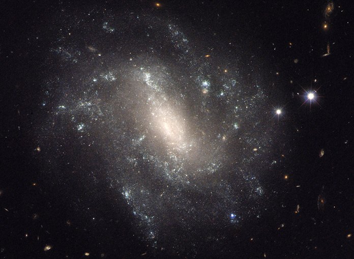 This image provided by NASA shows a barred spiral galaxy 130 million light-years away and is one of the measurements that astronomers used to come up with a faster rate of expansion of the universe. And if that new rate is correct, then scientists have to refigure some basic assumptions about the cosmos. (NASA via AP)