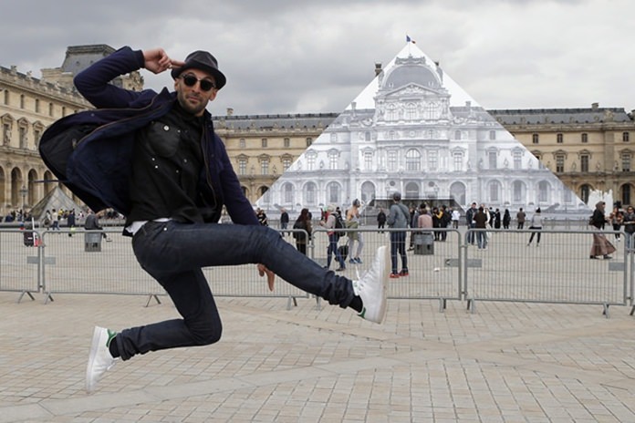 Street artist JR poses in front of his trompe l’oeil installation on the Louvre Pyramid in Paris, Tuesday, May 24. (AP Photo/Francois Mori)