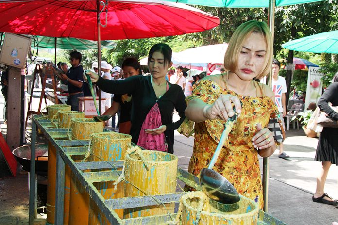 Devout Buddhists make merit by helping to make candles for the beginning of Buddhism’s version of Lent.