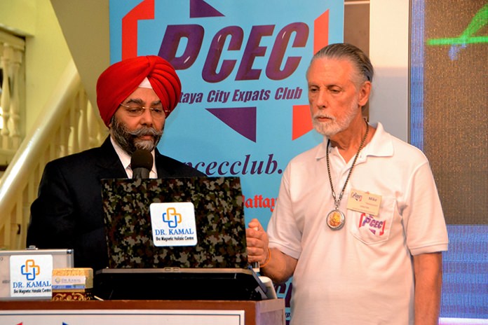 PCEC member Michael Warner holds the sensor wand for the Quantum Resonance Magnetic Analyzer in his hand as Dr. Kamal demonstrates that it only takes 59 seconds to obtain a complete its diagnoses for 39 health conditions.