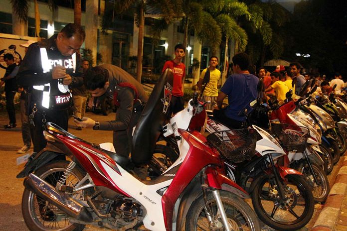 Police check motorcycle registrations as busted Kuwaitis wait for processing in the background.
