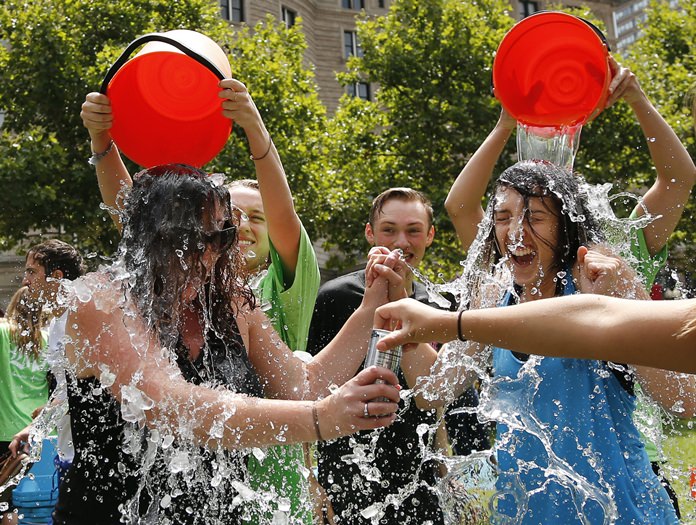 In this Aug. 7, 2014, file photo, two women get doused during the ice bucket challenge at Boston’s Copley Square to raise funds and awareness for ALS. The ALS Association says money raised through the challenge helped fund a project that has discovered a gene linked to the disease. (AP Photo/Elise Amendola, File)