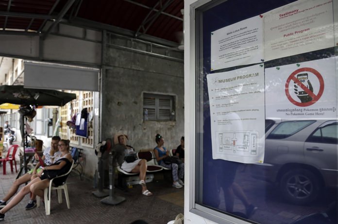 A warning sign, right, reading “No Pokemon Game” is stuck at a front gate of Tuol Sleng genocide museum, in Phnom Penh, Cambodia, Wednesday, Aug. 10. (AP Photo/Heng Sinith)