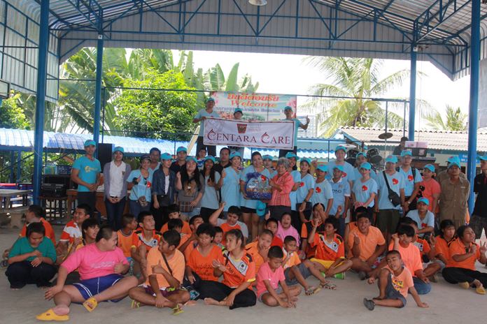 Staff and children gather around as Daranart Nuchaikaew (centre), Director of Human Resources presents a gift basket to Boonchu Muangmaithong (Khru Boonchu), caretaker of the children.