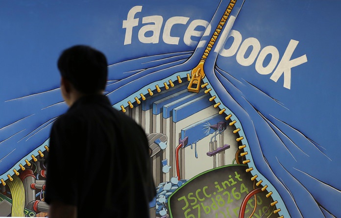 In this June 11, 2014, file photo, a man walks past a mural in an office on the Facebook campus in Menlo Park, Calif. Facebook is taking an aggressive new tack that blocks ad blockers on the desktop version of its service, insisting that well-made, relevant ads can be “useful.” (AP Photo/Jeff Chiu, File)