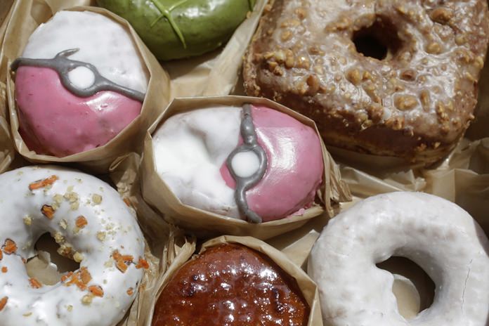 Pecha Berry Pokeseed doughnuts, top left and center, are displayed in a box of doughnuts from Doughnut Plant, in New York. From doughnut shops to zoos, businesses and organizations are finding creative ways to capitalize on “Pokemon Go.” (AP Photo/Mark Lennihan)