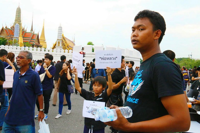 9-year-old Kerkrith holds a sign that reads “Sattahip Loves Our Father” as he helps serve the food.