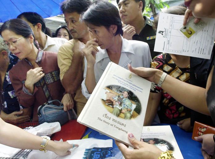 People queue up to buy a copy of “The Story of Thongdaeng,” written by His Majesty King Bhumibol Adulyadej about a stray dog he adopted. (AP Photo/Apichart Weerawong)