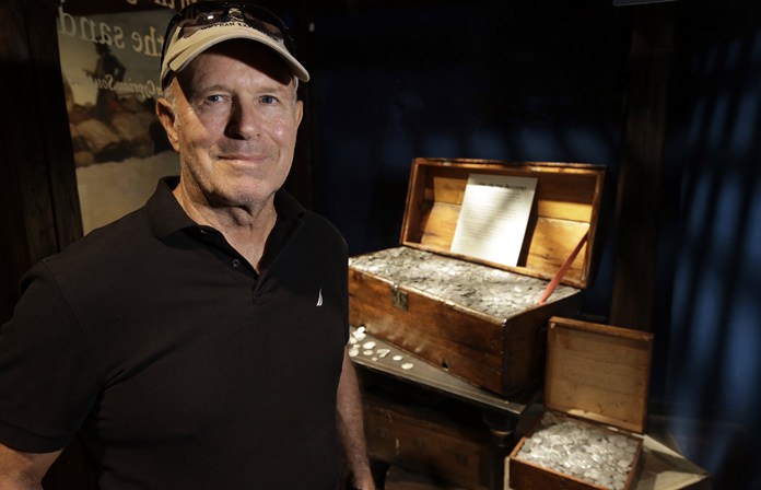 Undersea explorer Barry Clifford stands next to a display case containing silver coins recovered from the wreckage of the pirate ship Whydah Gally, at the Whydah Pirate Museum, in Yarmouth, Mass. (AP Photo/Steven Senne)