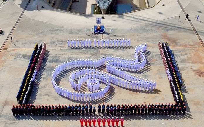 400 sailors in their dress whites line up in the shape of the Thai numeral 9 in front of HTMS Narathiwat.