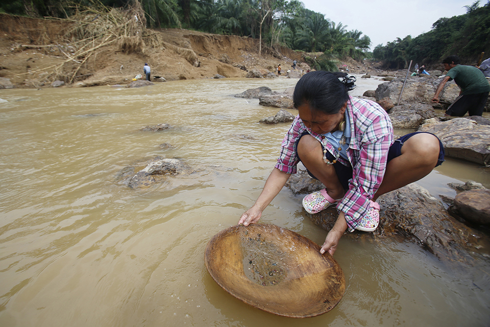 In this Jan. 19, 2017, photo, locals pan for gold in the Klong Thong, or "Golden Canal" in Prachuap Khiri Khan province, southern Thailand. The canal, expanded by devastating flash floods, has been washing up gold for villagers whose businesses have been swept away. (AP Photo/Sakchai Lalit)