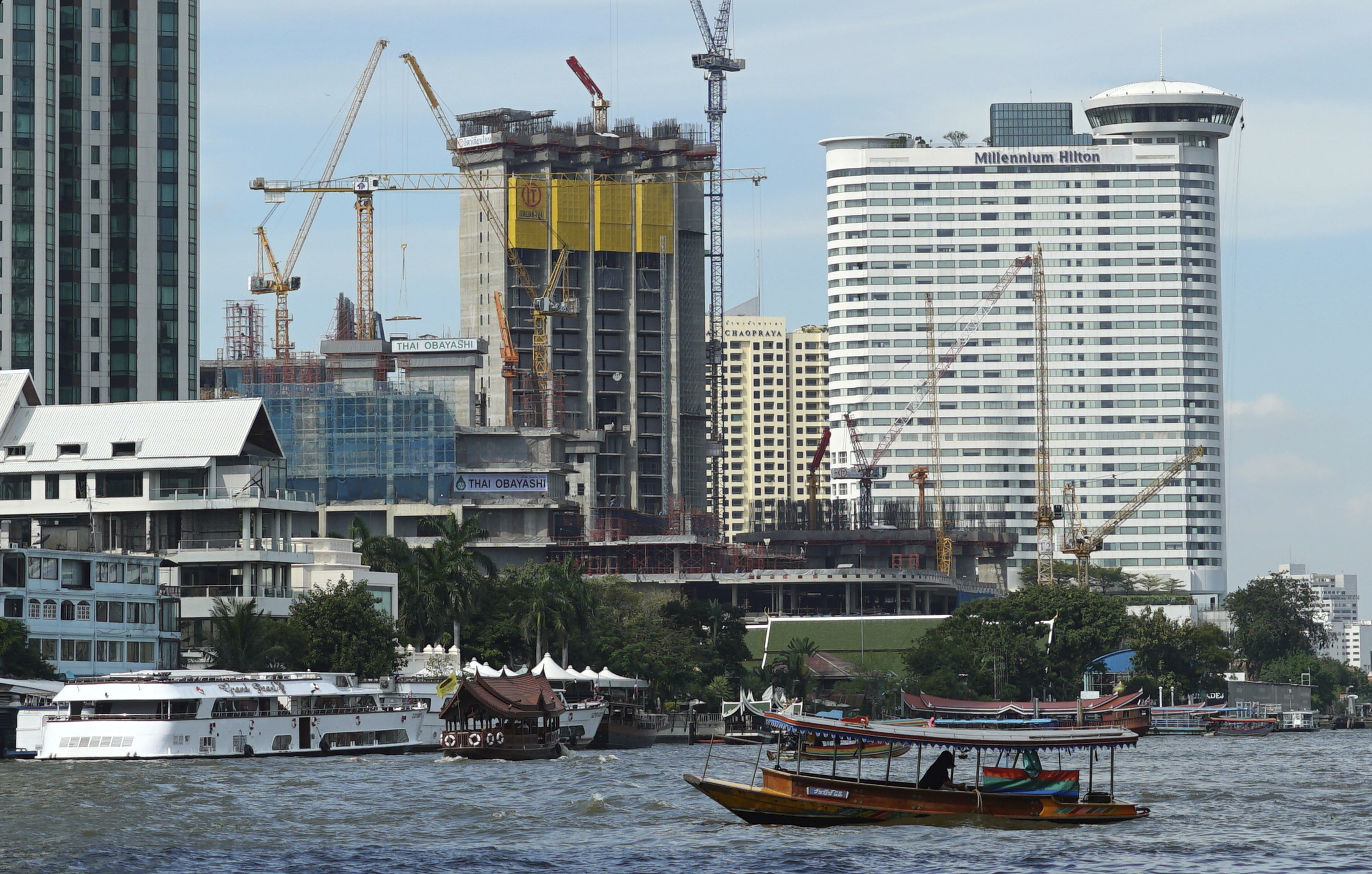 A riverboat taxi crosses the Chao Phraya River in front of massive construction projects Wednesday, Jan. 18, 2017, in Bangkok. A United Nations report says Asia's economic outlook for 2017 is strong despite slowing global growth due to sluggish international trade and investment. (AP Photo/Dake Kang)