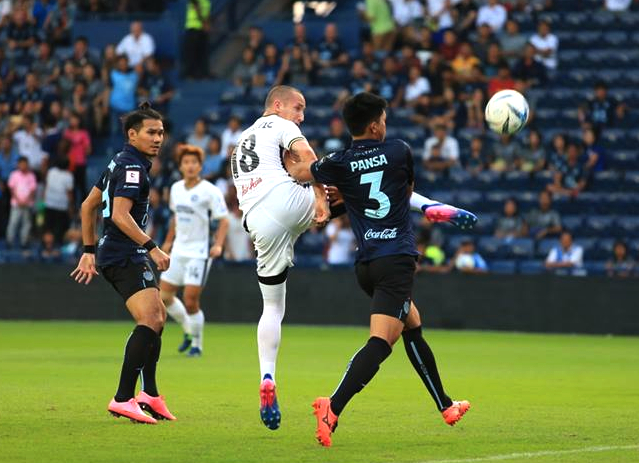 Pattaya United’s Miloš Stojanović (18) challenges for the ball with Buriram United’s Pansa Hemviboon (3) during the second half of their Thai Premier League fixture at the I-Mobile ‘Thunder Castle’ stadium in Buriram, Saturday, Feb. 25. (Photo courtesy Pattaya United)