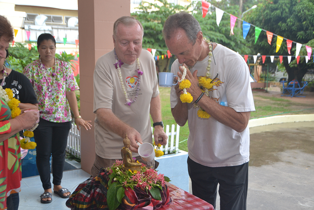 Lewis Underwood and Erle Kershaw from Jesters Care for Kids pour fragrant water on the Buddha statue as part of the bathing the Buddha image ritual during the Fountain of Life’s Songkran celebration.