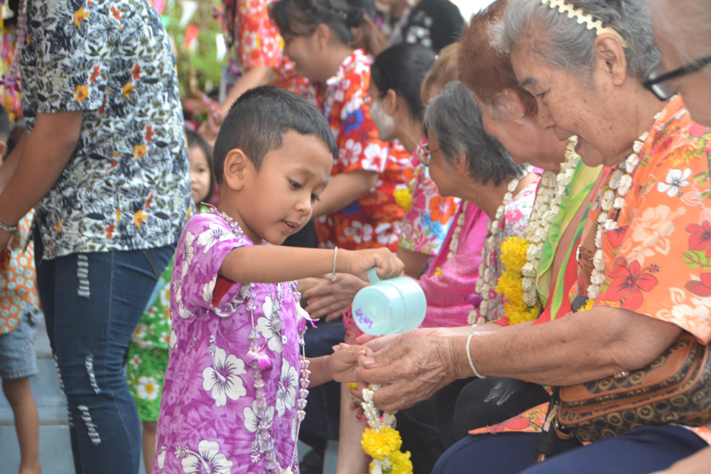 A young man politely pours water on the hands of an elder and receives a blessing in return.